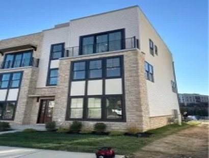 Modern three-story townhouse with large windows and stone detailing.
