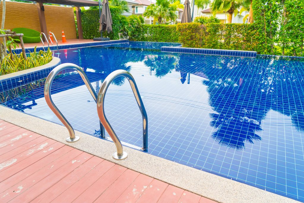 Luxury outdoor swimming pool with ladder and tiled deck at a residential or resort property.