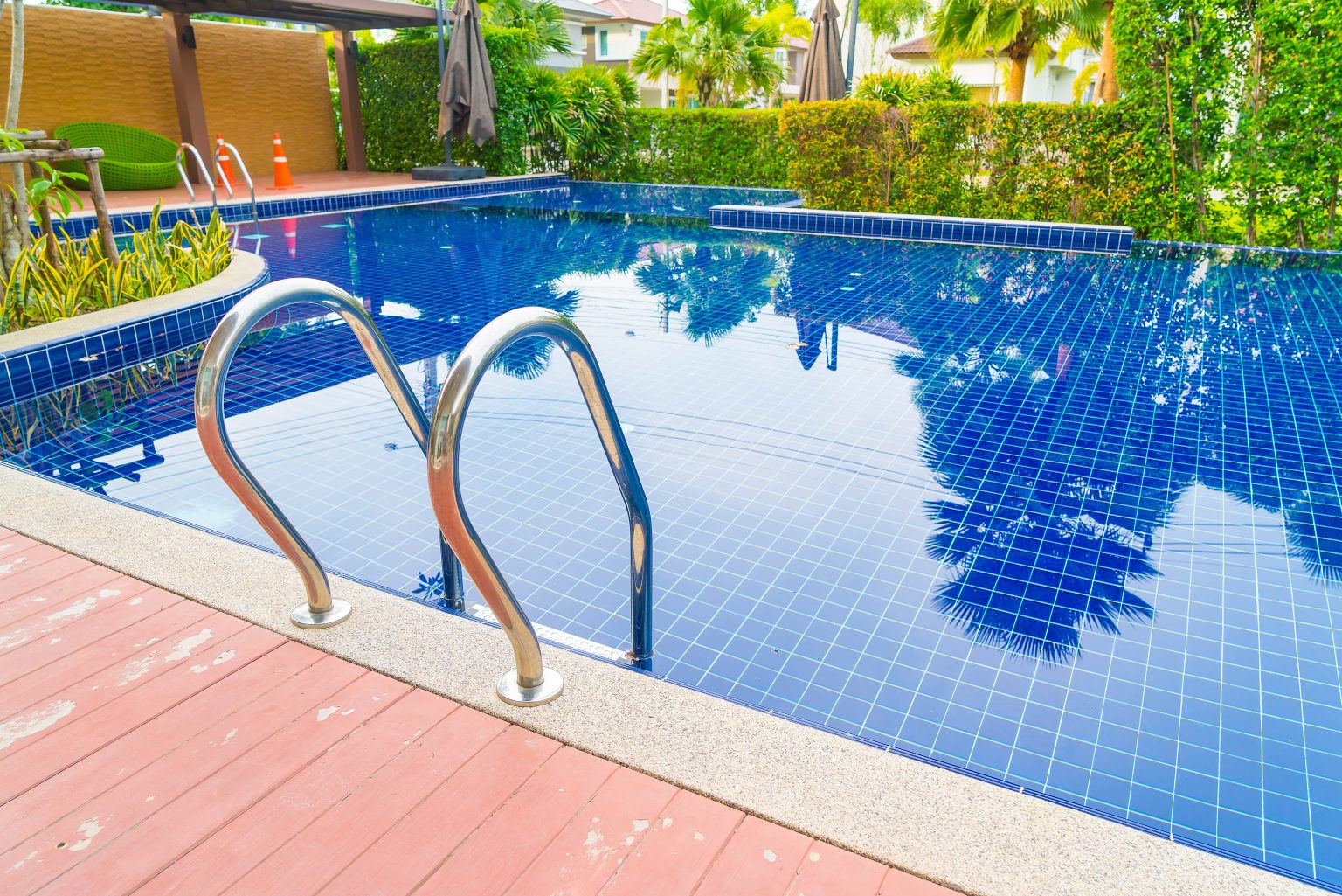 Luxury outdoor swimming pool with ladder and tiled deck at a residential or resort property.